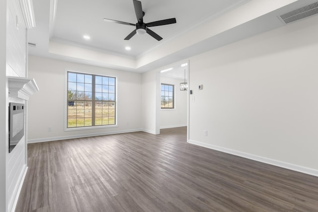 unfurnished living room featuring visible vents, crown molding, baseboards, dark wood finished floors, and a tray ceiling