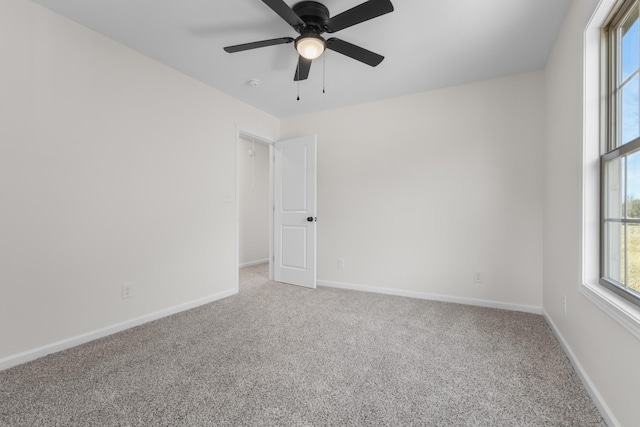 unfurnished room with a ceiling fan, baseboards, and light carpet