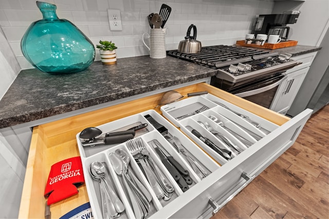 interior details with hardwood / wood-style floors, tasteful backsplash, and stainless steel gas stove