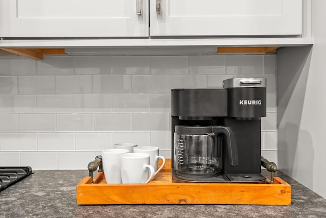 details with white cabinets, dark stone countertops, and backsplash