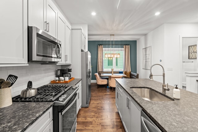 kitchen featuring dark hardwood / wood-style floors, hanging light fixtures, sink, white cabinetry, and appliances with stainless steel finishes