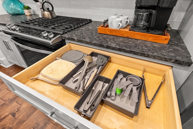 room details featuring dark stone countertops, hardwood / wood-style flooring, tasteful backsplash, and high end stove