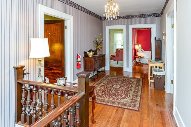 hall with hardwood / wood-style floors and an inviting chandelier