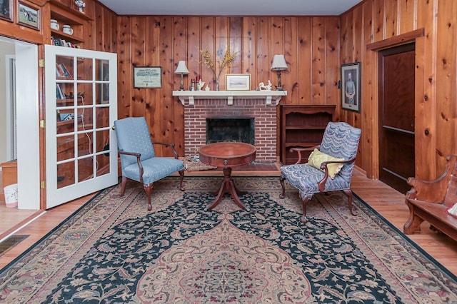 living area with hardwood / wood-style flooring, wood walls, and a fireplace