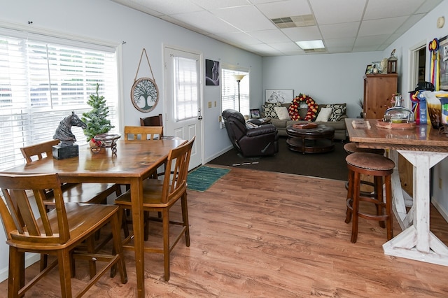 dining space featuring light wood-type flooring and a drop ceiling