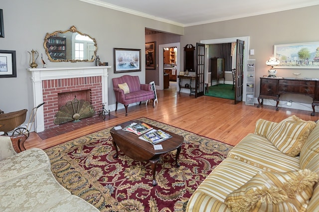 living room with hardwood / wood-style floors, ornamental molding, and a brick fireplace