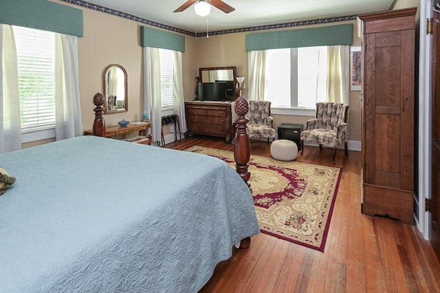 bedroom with hardwood / wood-style floors, ceiling fan, and multiple windows