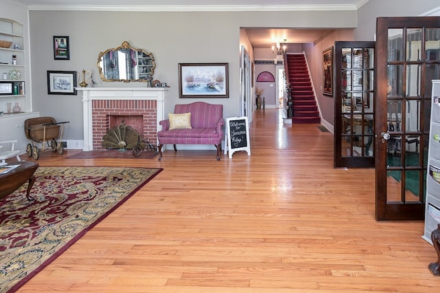 living room featuring a fireplace, built in shelves, an inviting chandelier, and light hardwood / wood-style flooring