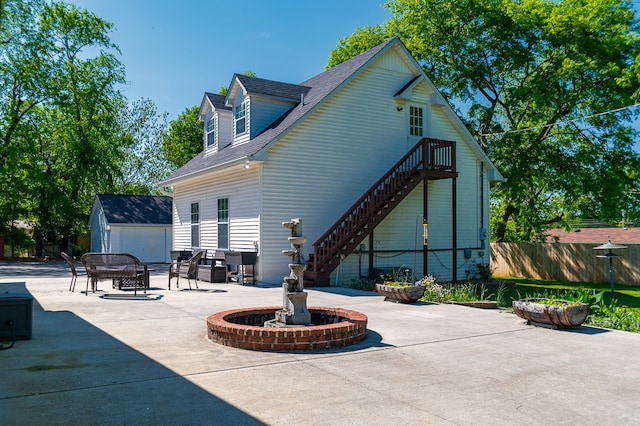 rear view of property with an outdoor structure and a patio area