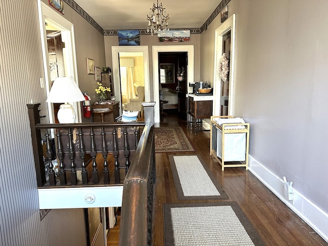 corridor featuring dark hardwood / wood-style flooring and an inviting chandelier