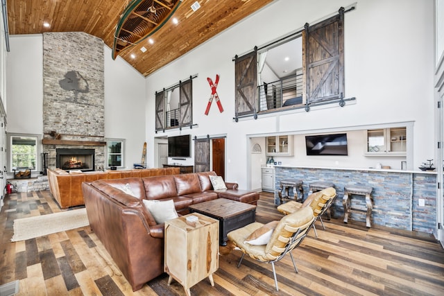 living room with a stone fireplace, hardwood / wood-style flooring, high vaulted ceiling, and wooden ceiling