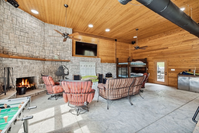 living room featuring a fireplace, wood walls, wood ceiling, and ceiling fan