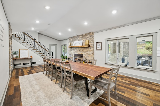 dining area featuring hardwood / wood-style floors, a large fireplace, vaulted ceiling, and ornamental molding