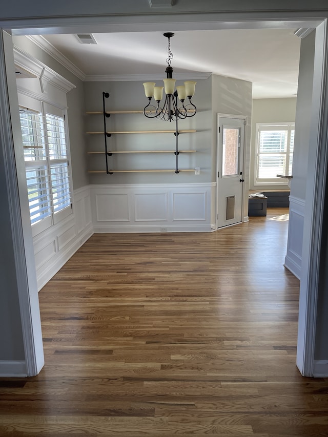 unfurnished dining area with a notable chandelier, ornamental molding, and dark hardwood / wood-style flooring