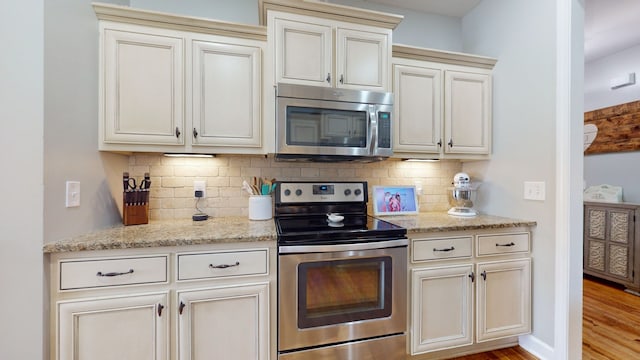 kitchen featuring appliances with stainless steel finishes, light stone countertops, decorative backsplash, and light hardwood / wood-style flooring