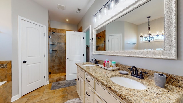 bathroom featuring an inviting chandelier, vanity, tile patterned flooring, and tiled shower