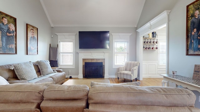 living room featuring a fireplace, crown molding, vaulted ceiling, and light hardwood / wood-style flooring