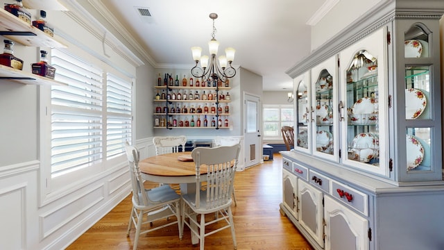 dining room with ornamental molding, a notable chandelier, and light hardwood / wood-style floors