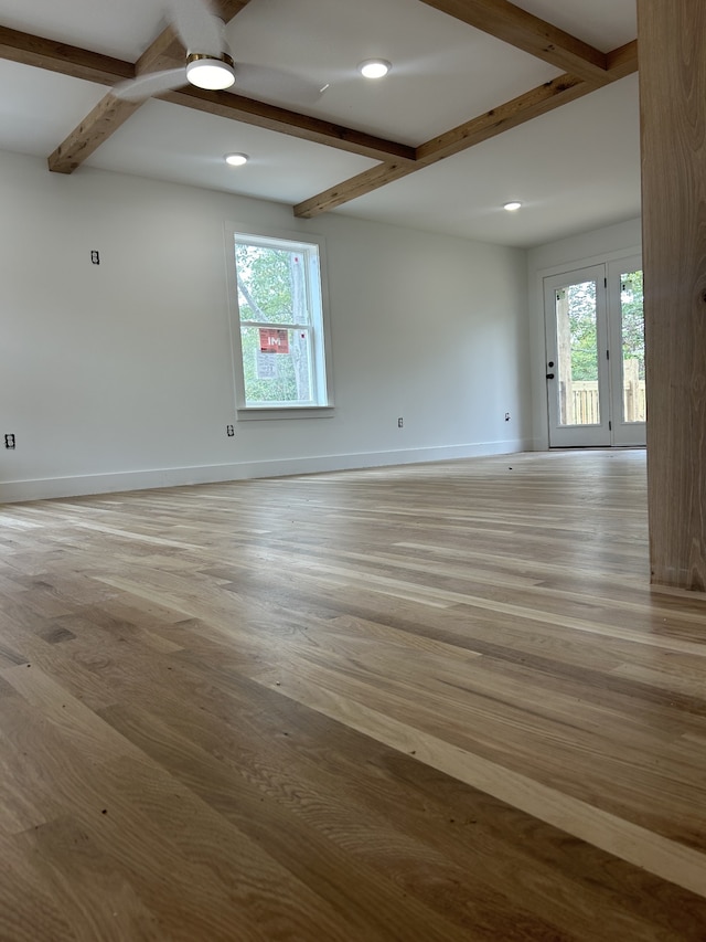 unfurnished room with beamed ceiling and light hardwood / wood-style flooring