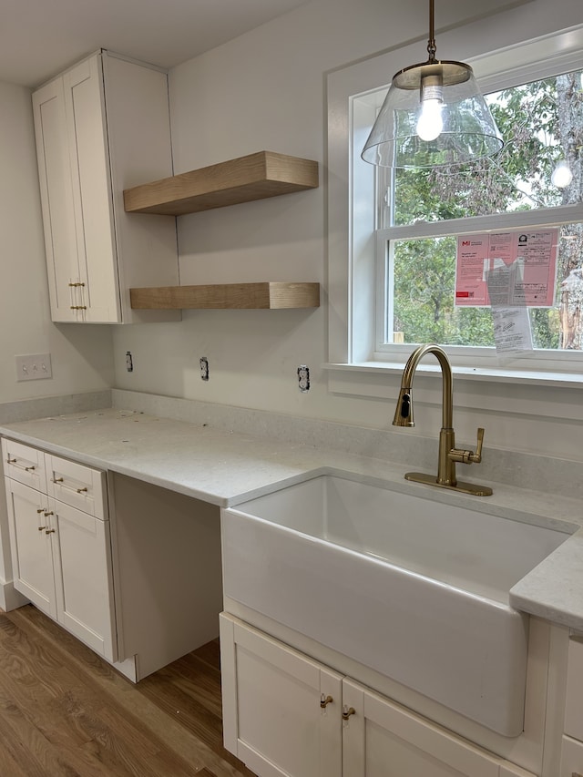 kitchen featuring light stone countertops, white cabinets, dark wood-type flooring, sink, and pendant lighting