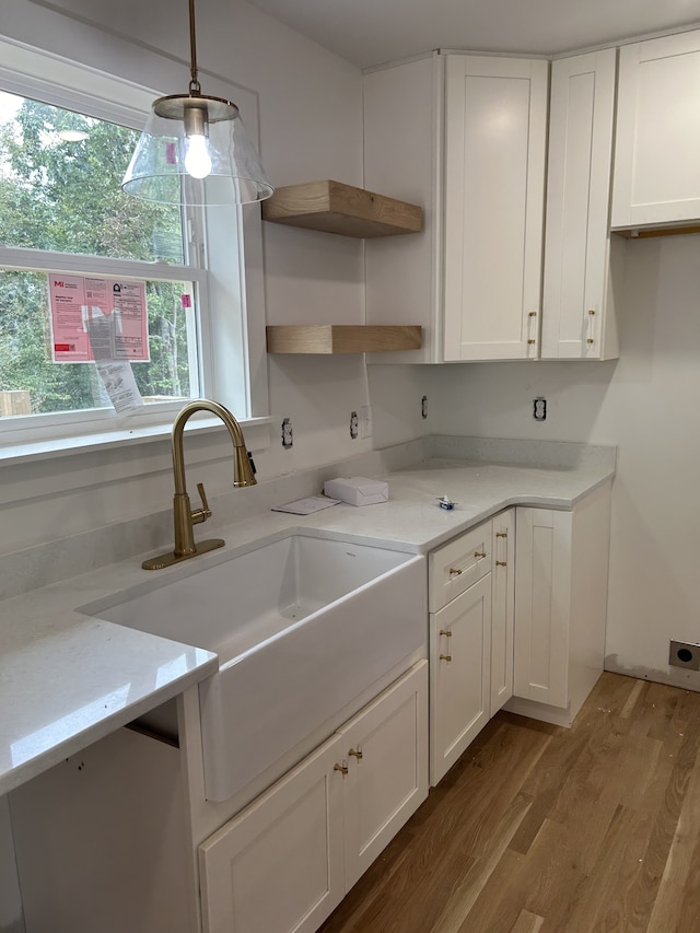 kitchen with pendant lighting, light stone countertops, hardwood / wood-style floors, and white cabinetry