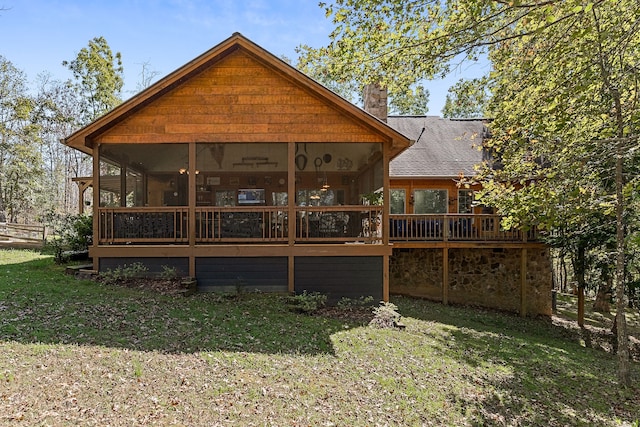 rear view of property featuring a sunroom, a lawn, and a deck