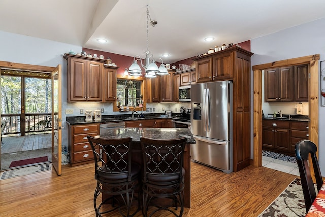 kitchen featuring appliances with stainless steel finishes, a wealth of natural light, a center island, and light hardwood / wood-style flooring