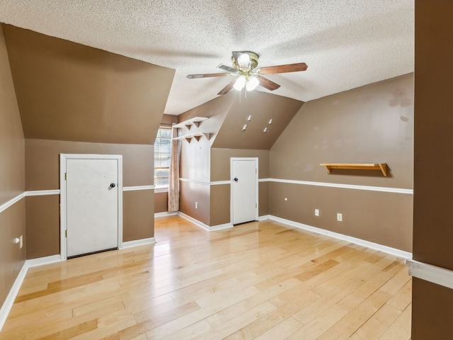 additional living space featuring light hardwood / wood-style floors, lofted ceiling, a textured ceiling, and ceiling fan