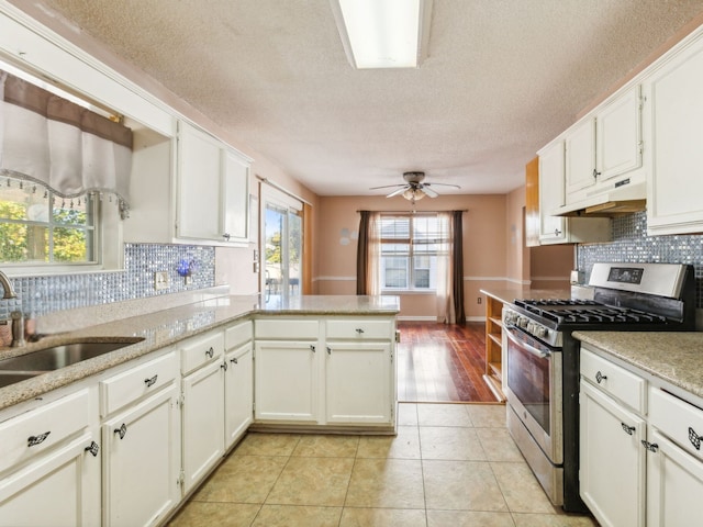 kitchen featuring kitchen peninsula, stainless steel gas range oven, and white cabinets