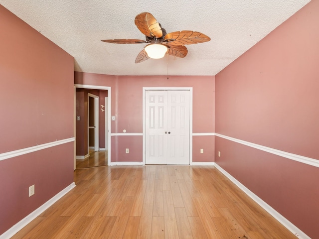 spare room with ceiling fan, a textured ceiling, and light hardwood / wood-style flooring