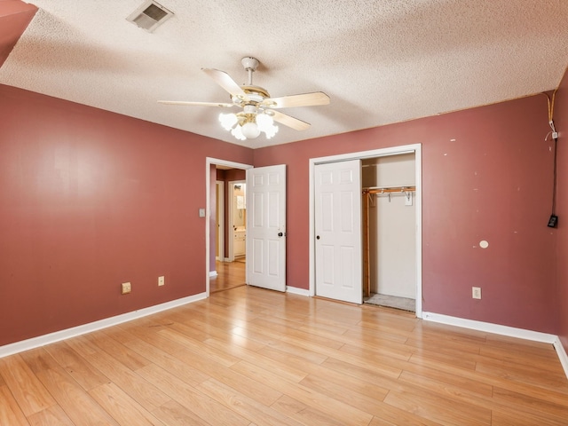 unfurnished bedroom with light hardwood / wood-style flooring, a textured ceiling, a closet, and ceiling fan