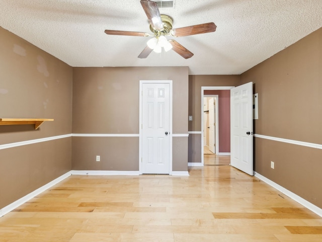 empty room with light hardwood / wood-style floors, a textured ceiling, and ceiling fan