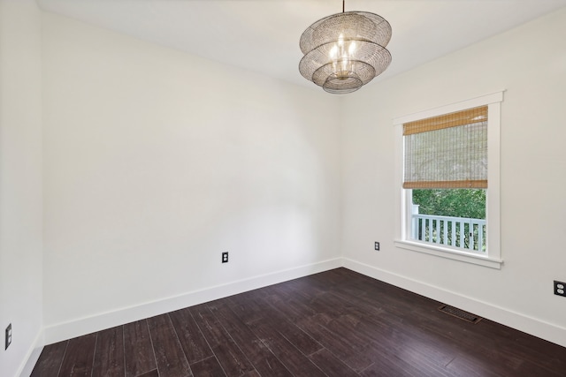 unfurnished room featuring an inviting chandelier and dark wood-type flooring