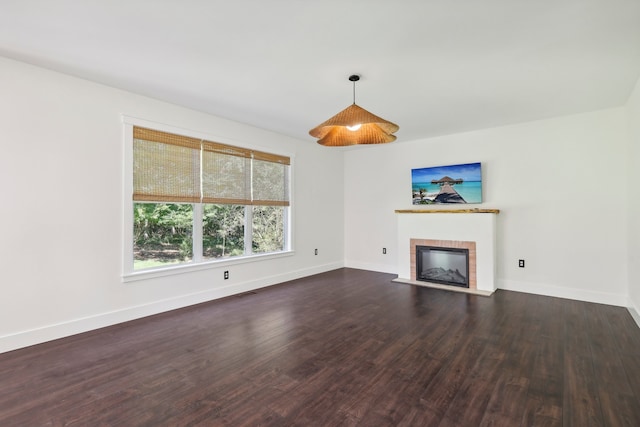 unfurnished living room with a brick fireplace and dark wood-type flooring