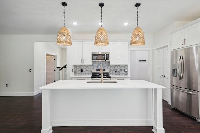 kitchen featuring a center island with sink, dark wood-type flooring, decorative light fixtures, and stainless steel appliances