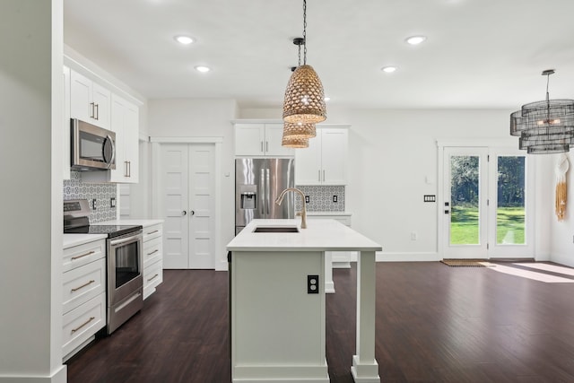 kitchen with hanging light fixtures, a kitchen island with sink, sink, and stainless steel appliances