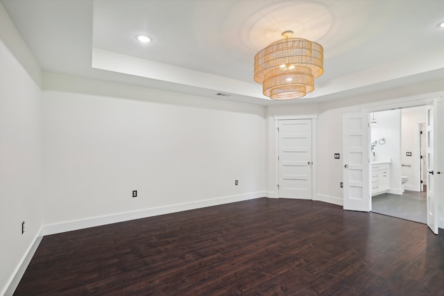 unfurnished room featuring a raised ceiling and dark wood-type flooring