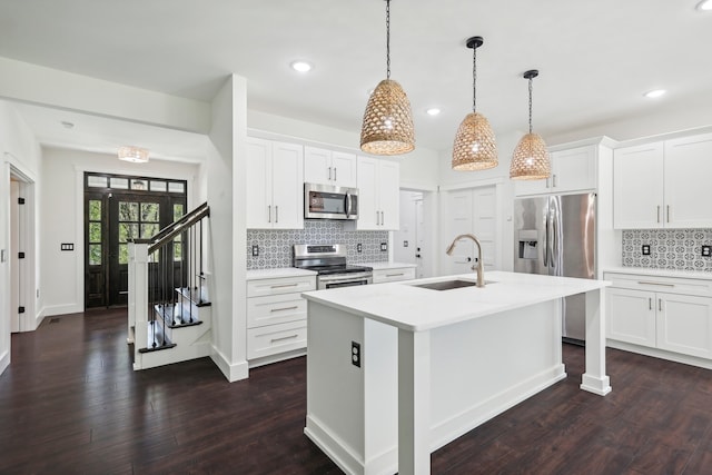 kitchen with an island with sink, white cabinetry, stainless steel appliances, and dark hardwood / wood-style flooring