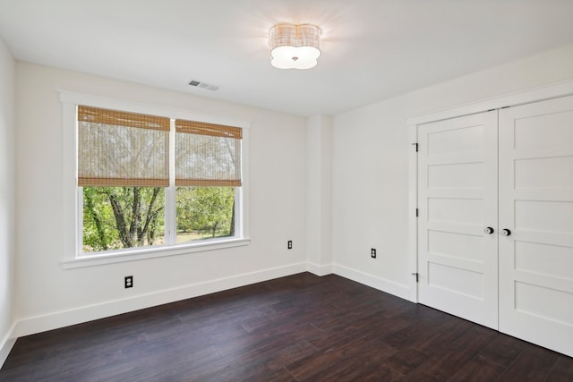 unfurnished bedroom with dark wood-type flooring and a closet