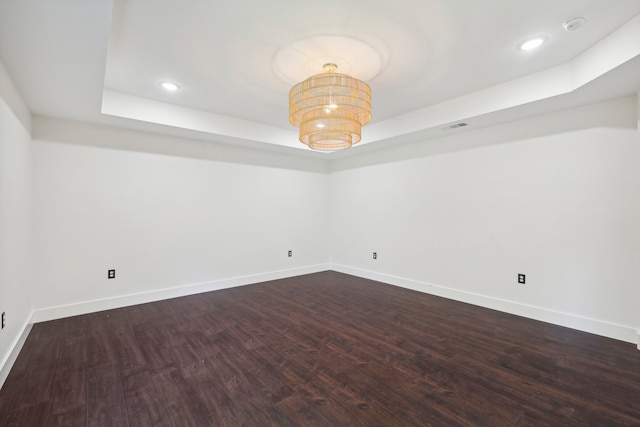 unfurnished room featuring dark hardwood / wood-style floors and a tray ceiling