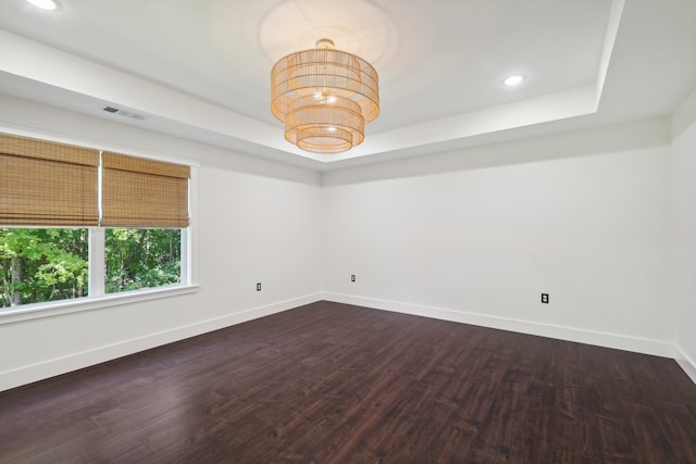 unfurnished room featuring dark wood-type flooring and a tray ceiling