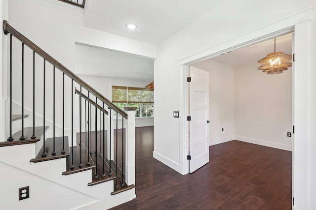 stairway with an inviting chandelier and wood-type flooring