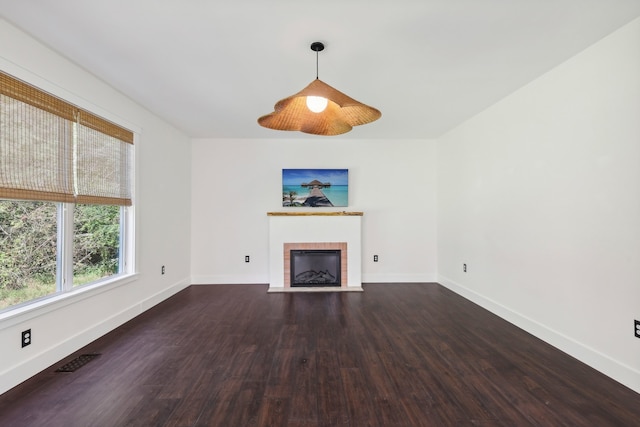 unfurnished living room with a brick fireplace and dark wood-type flooring