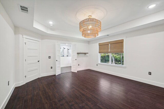 unfurnished living room featuring a tray ceiling and dark hardwood / wood-style floors