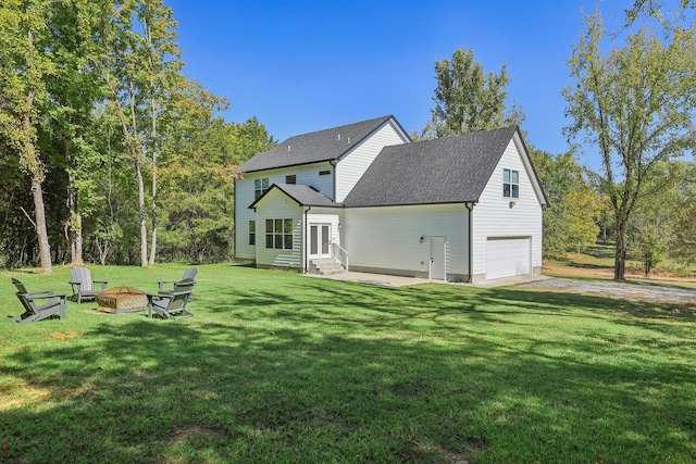 rear view of property with an outdoor fire pit, a garage, and a lawn