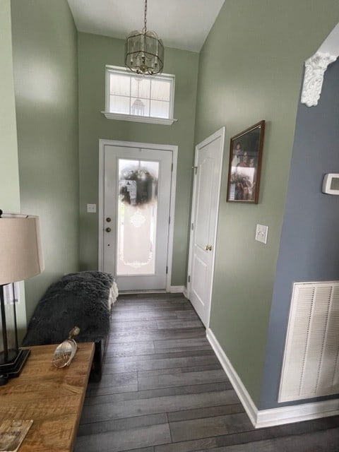 foyer featuring a towering ceiling, dark hardwood / wood-style floors, and an inviting chandelier