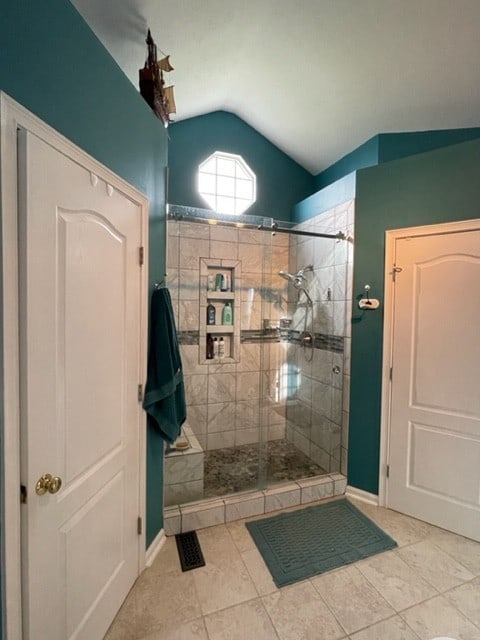 bathroom with tile patterned flooring, lofted ceiling, and walk in shower