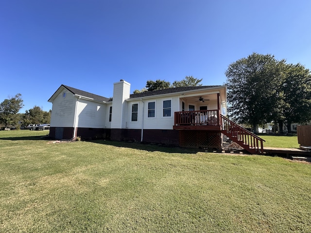 back of property featuring ceiling fan and a yard