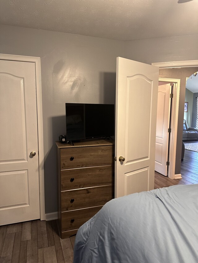 bedroom with dark hardwood / wood-style floors and a textured ceiling