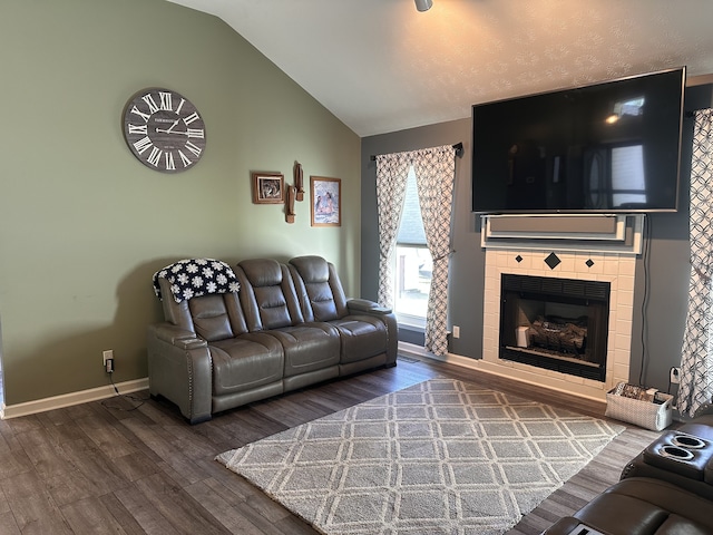 living room with a tile fireplace, vaulted ceiling, and hardwood / wood-style flooring